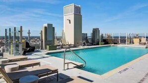 A rooftop pool with lounge chairs, a glass balustrade, and a cityscape view. - 19th Floor Midtown Sky Suite | Free Parking | Gym (Atlanta)