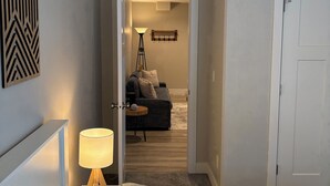 Ein Hotelzimmer mit einem Bett, einem Nachttisch, einer Lampe und einem Sofa im angrenzenden Wohnbereich sowie einer Tür zu einem weiteren Zimmer.