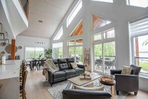 A spacious living room with a large black leather sofa, a coffee table, and a dining area with a table and chairs.