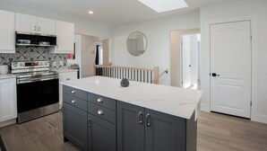 A modern kitchen with a central island, dark grey cabinets, white countertops, and a skylight. - Dorado House-Cottage (Kawartha Lakes)