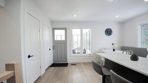 A modern kitchen with a white countertop, grey chairs, and a black clock on the wall. - Dorado House-Cottage (Kawartha Lakes)