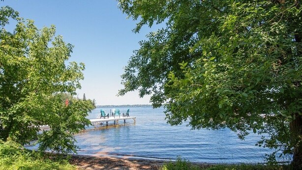 A lakeside dock with chairs and a table, surrounded by trees and grassy areas. - Dorado House-Cottage (Kawartha Lakes)