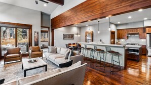 Un amplio salón con techo de madera, un sofá grande y una mesa de comedor.
