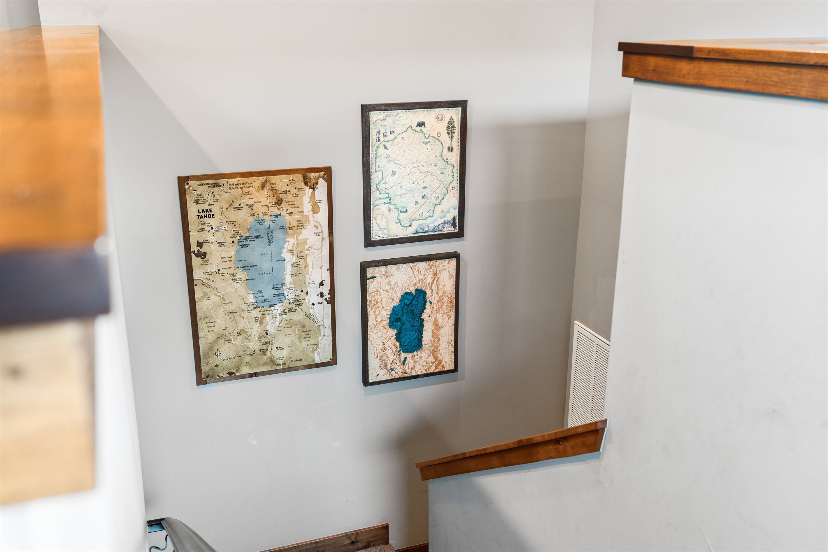 Een trap met drie inlijstingen van kaarten aan de muur.