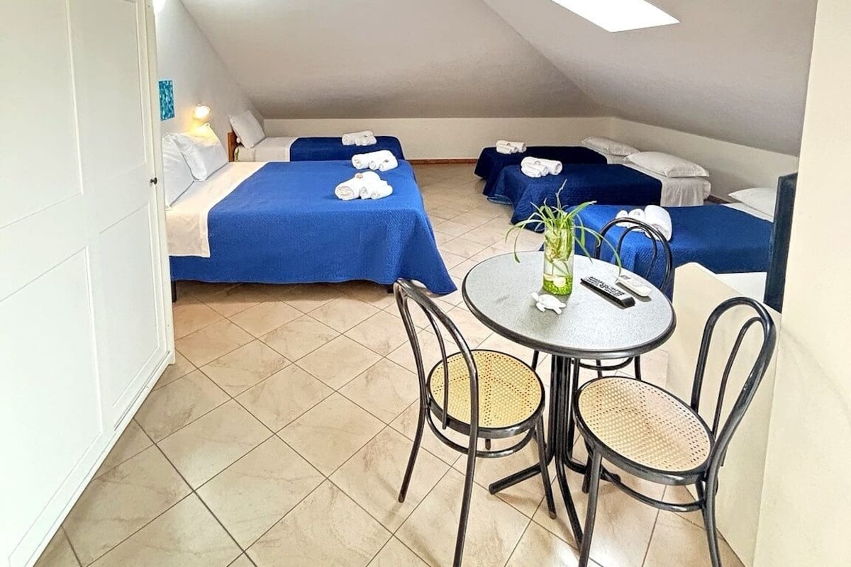 A room with two beds, a round table with chairs, and a door.