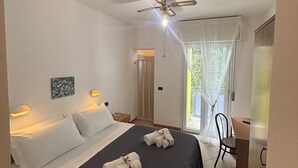 A hotel room with a bed, a desk, a chair, a ceiling fan, and a window with curtains. - Hotel Dream (Rimini)