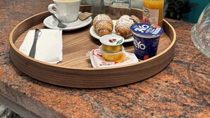 A tray with breakfast items including croissants, a cup of coffee, a glass of orange juice, and a yogurt container on a granite countertop. - Hotel Dream (Rimini)
