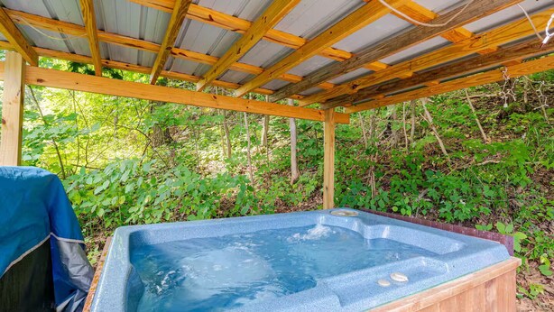 Un bain à remous sous une pergola en bois, avec un décor naturel et boisé en arrière-plan.