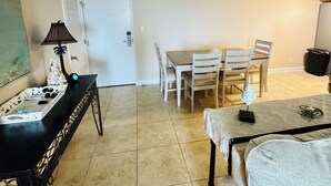 A compact living space with a dining area, a sofa, a lamp, and a door leading to another room. - GULF FRONT relaxing condo on GORGEOUS Pensacola Beach. Private pool,low density! (Gulf Breeze)
