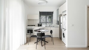 A modern kitchen with a dining area, featuring a stove, oven, sink, and a built-in washing machine. - Chic 4 Keren Hayesod (Jerusalem)