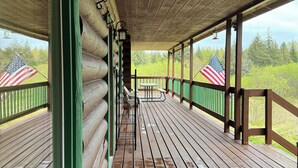 Une terrasse en bois couverte, dotée d’une rambarde verte, d’une table de pique-nique et de deux drapeaux américains.