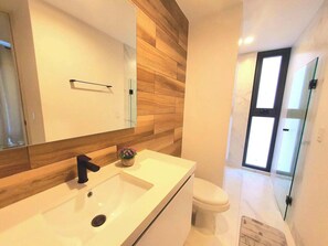 A modern bathroom with a wooden accent wall, a white sink, and a toilet.