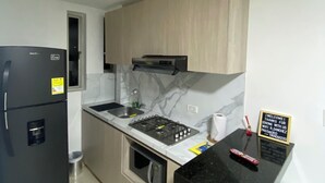 A compact kitchen with a black refrigerator, a gas stove, and wooden cabinets.