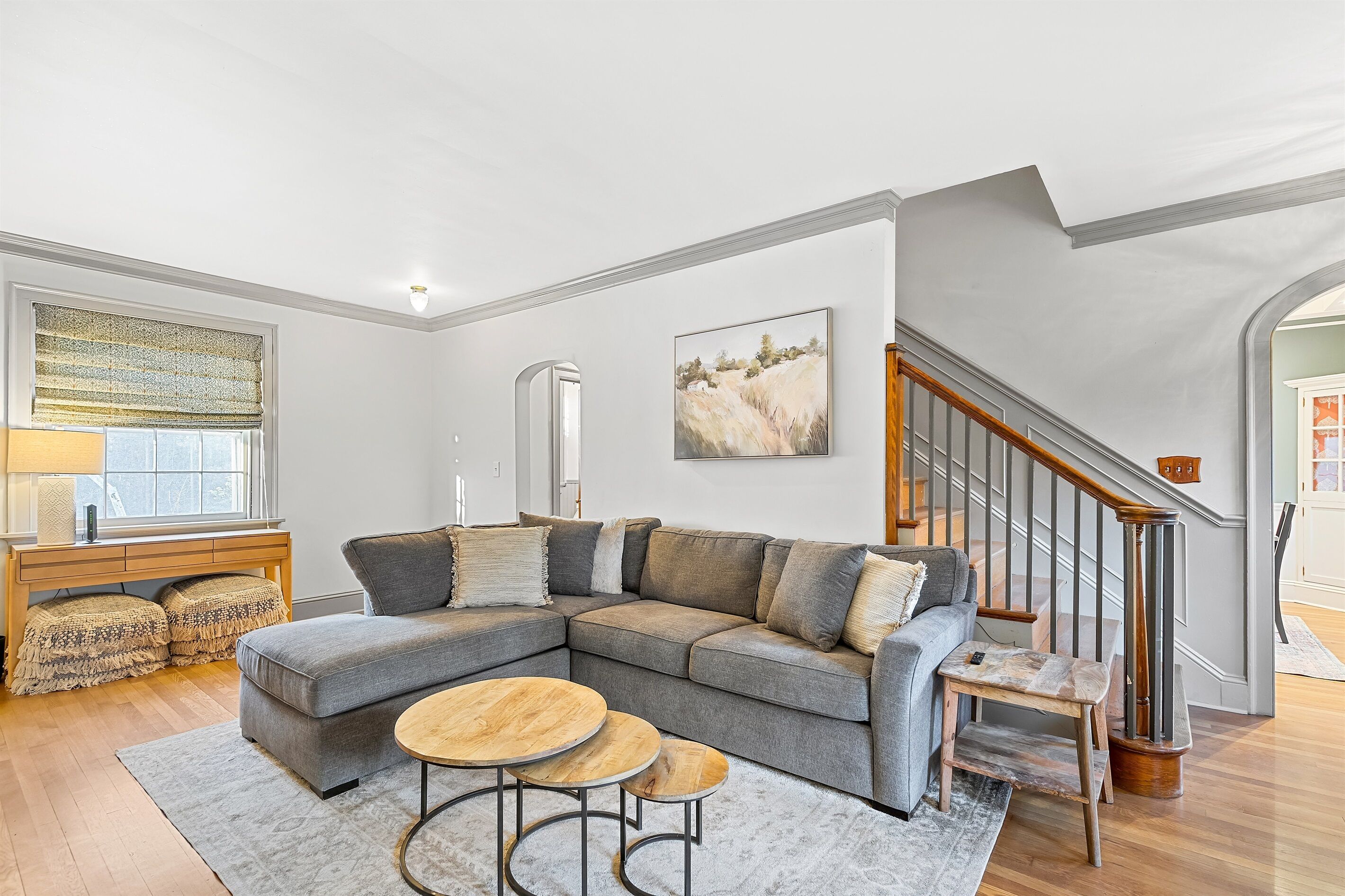 A modern living room with a sectional sofa, a wooden coffee table, and a staircase.