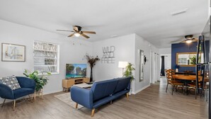 Uma sala de estar moderna com um sofá azul, piso de madeira e ventilador de teto.