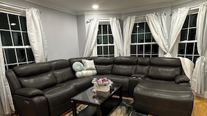 A modern living room with a sectional sofa, a glass coffee table, and a patterned rug. - North End Retreat (Manchester)