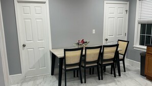 A dining area with a marble floor, a white table, and four chairs with woven seats. - North End Retreat (Manchester)