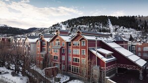 A multi-story hotel with a red facade, large windows, and a sloped roof.