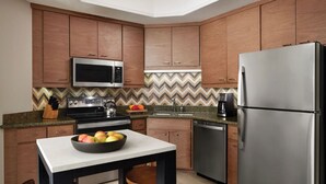 A modern kitchen with wooden cabinets, stainless steel appliances, a microwave, stove, and a refrigerator.