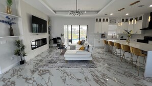 Una cocina moderna con armarios blancos, una isla central e iluminación colgante.