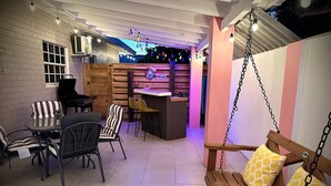 A cozy indoor seating area with a wooden swing, striped chairs, and a bar counter. - NEW 2 Bed2 Bath Tropical Villa.Ultimate Escape! Private Pool.Covered Patio & BBQ (Savaneta)