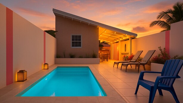 A rectangular swimming pool with a tiled deck, surrounded by a low wall. There are two lounge chairs and a small table with a lamp. - NEW 2 Bed2 Bath Tropical Villa.Ultimate Escape! Private Pool.Covered Patio & BBQ (Savaneta)