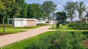 Un espacio exterior moderno con un sendero de grava que lleva a una hilera de viviendas modulares.