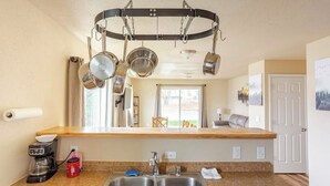 Una cucina con una rastrelliera pensile per pentole, una macchina da caffè e un lavandino.