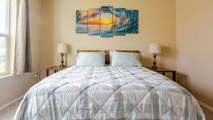 Camera da letto con un letto, due comodini, un quadro appeso al muro e una finestra con tende.