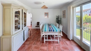 A dining area with a large table, chairs, a cabinet, and a view through a glass door. - Maison 5 Cantons Anglet (ANGLET)