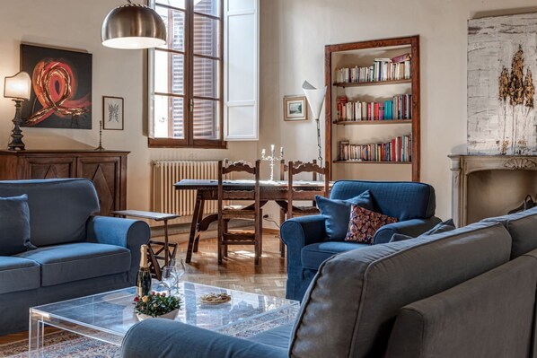 A living room with a sofa, a coffee table, a bookshelf, and a fireplace.