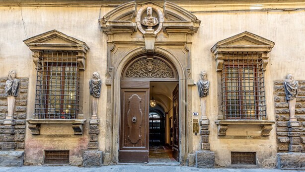 A building facade with a central entrance, flanked by statues and ornate window grills. - Dimora Savelli - Sweet Dreams in Florence (Firenze)