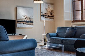 Una sala de estar moderna con un sofá, una mesa de centro, un televisor y arte abstracto en la pared.