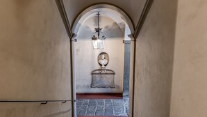 A corridor with an arched ceiling, a stone floor, a bust sculpture, and a wall-mounted light fixture. - Dimora Savelli - Sweet Dreams in Florence (Firenze)