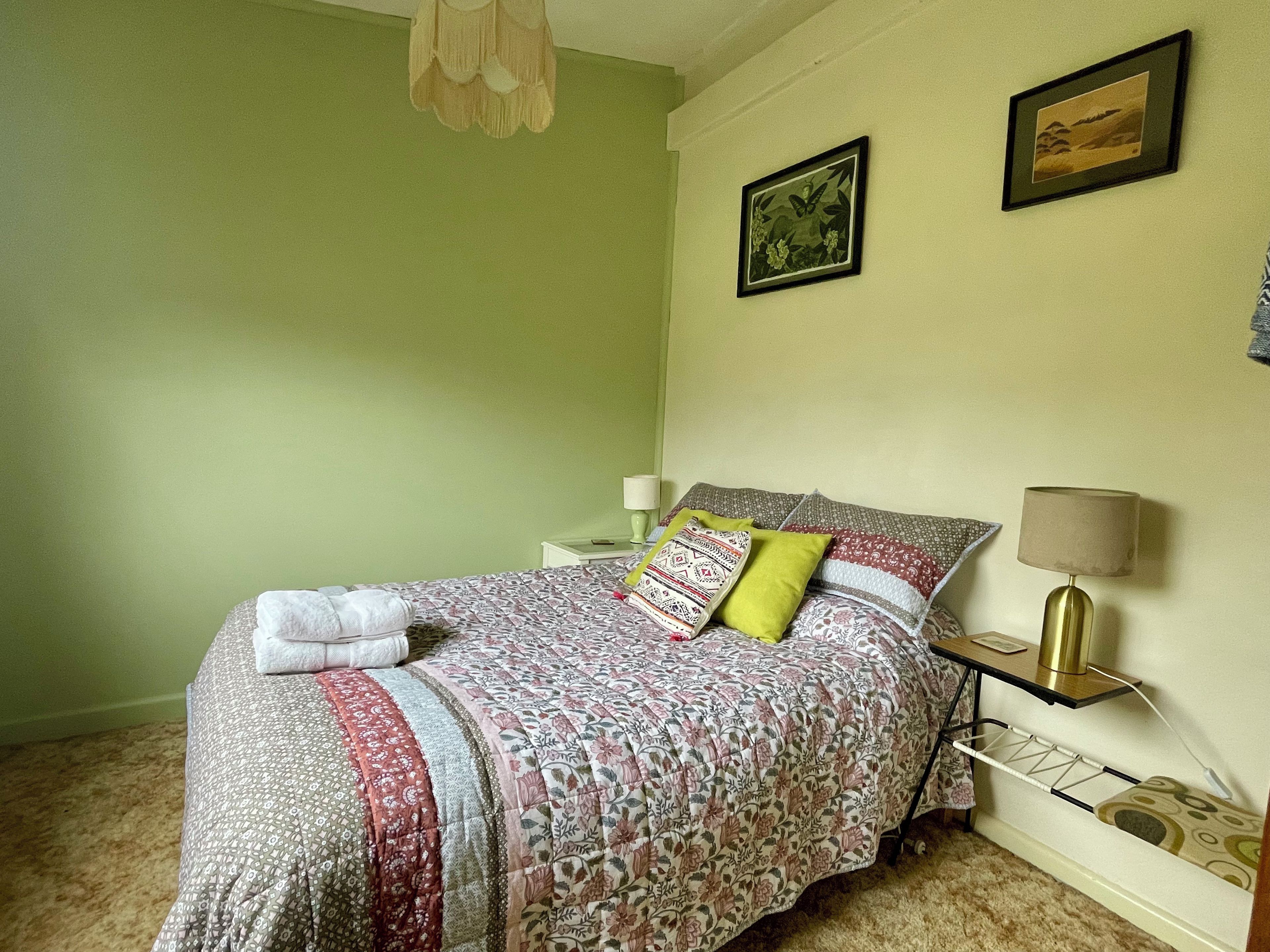 A neatly made bed with a floral comforter, two bedside lamps, and a small bedside table with a lamp.