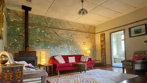 A spacious living room with a red sofa, patterned rug, and a decorative fireplace.