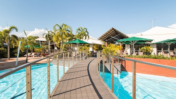 Ein Poolbereich mit Holzterrasse, Liegestühlen und Sonnenschirmen.