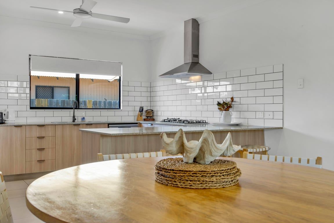 A modern kitchen with white subway tiles, a central island, and a dining table with a woven centerpiece.