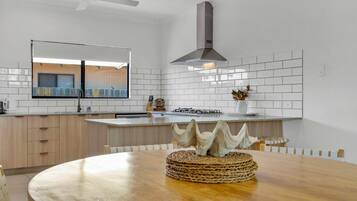 A modern kitchen with white subway tiles, a central island, and a dining table with a woven centerpiece.