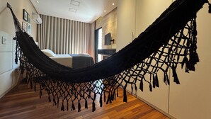 A modern hotel room with a hammock, wooden flooring, and a bed with a view of the city. - COP 30 TWO SUITES (Umarizal Belém)