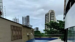 A modern building with a swimming pool and a tiled walkway. - COP 30 TWO SUITES (Umarizal Belém)