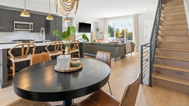 A modern kitchen with dark cabinets, a round dining table, and a chandelier. - Bright/Beautiful new townhome near Old Town Arvada/Quick access to the Mountains (Arvada)