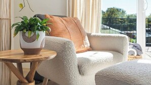 A cozy living area with a plush armchair, a small wooden table, and a potted plant. - Bright/Beautiful new townhome near Old Town Arvada/Quick access to the Mountains (Arvada)