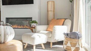 A cozy living room with a fireplace, a comfortable sofa, a matching ottoman, and a wicker basket. - Bright/Beautiful new townhome near Old Town Arvada/Quick access to the Mountains (Arvada)