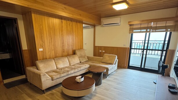 Un saló modern amb un sofà modular, dues taules de centre rodones, terres de fusta i una finestra gran amb vistes.