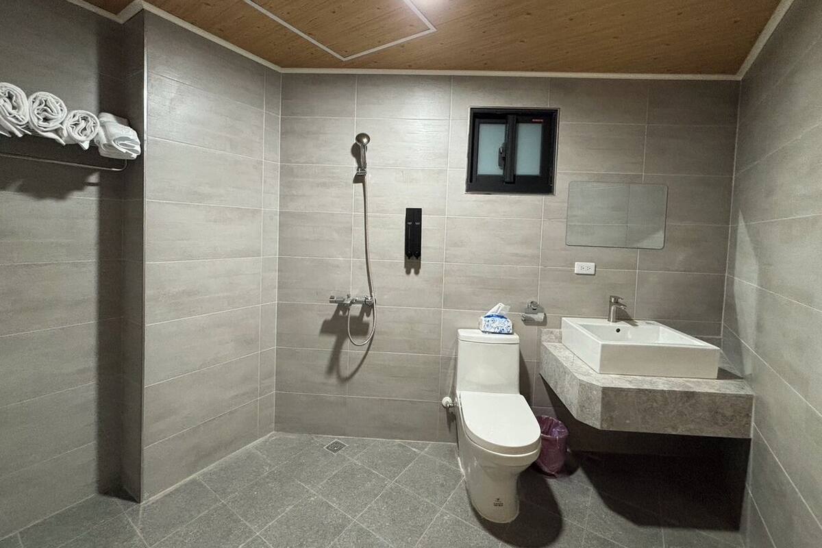 A modern bathroom with a shower, toilet, and sink.
