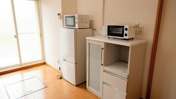 A small kitchenette with a microwave, refrigerator, and a cabinet.