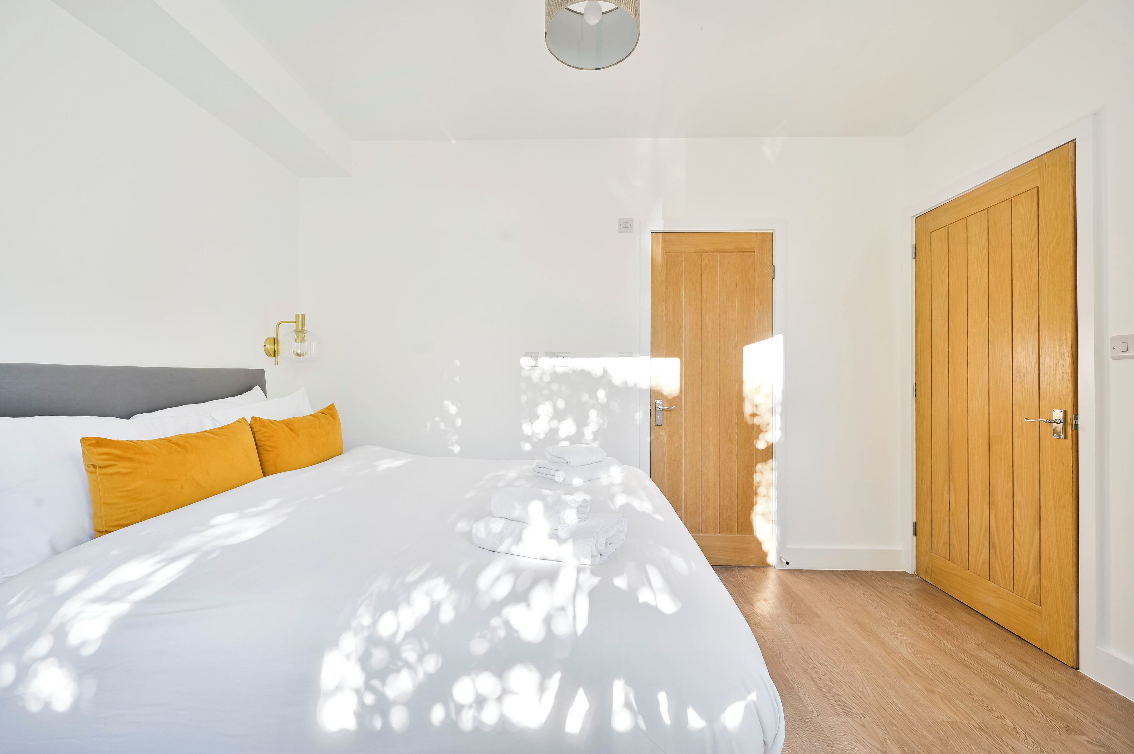 Un dormitorio con una cama, una puerta de madera y una lámpara.