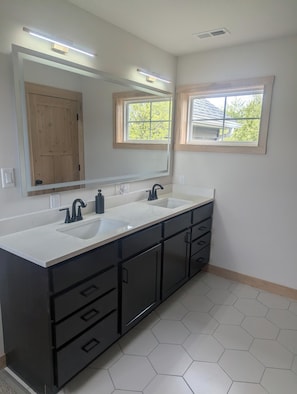 A bathroom with two sinks, a large mirror, and a window.