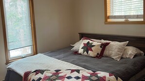 Un dormitorio con cama, ventana y cabecera de madera.